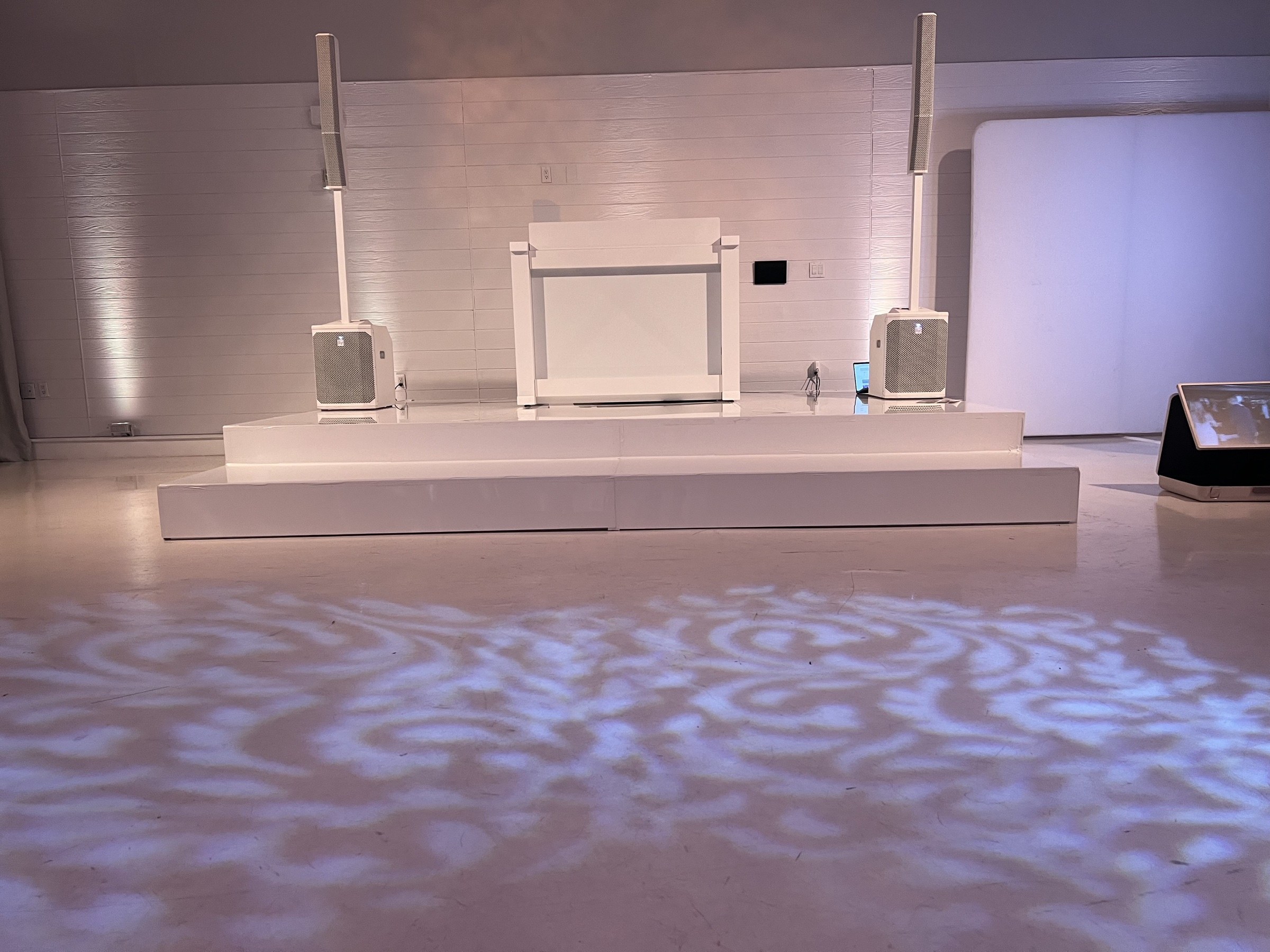 White stage and DJ booth with gobo lighting on the dance floor at the Ravel Hotel