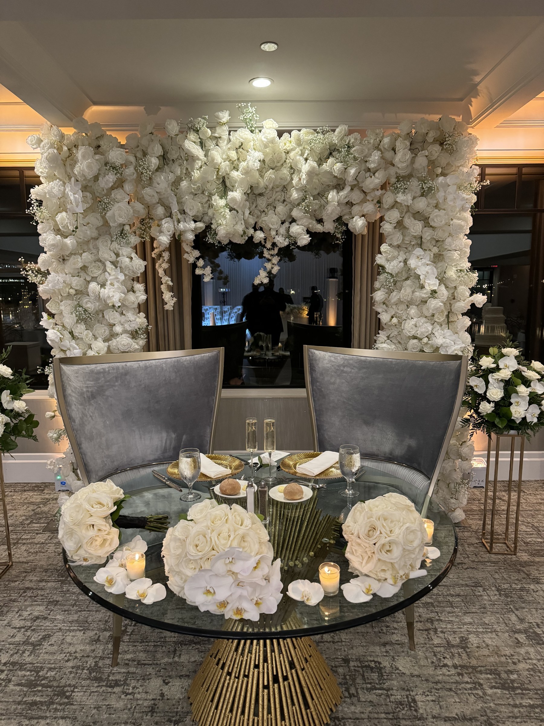 Sweetheart table beneath a white floral arch at Water's Edge, Centerport