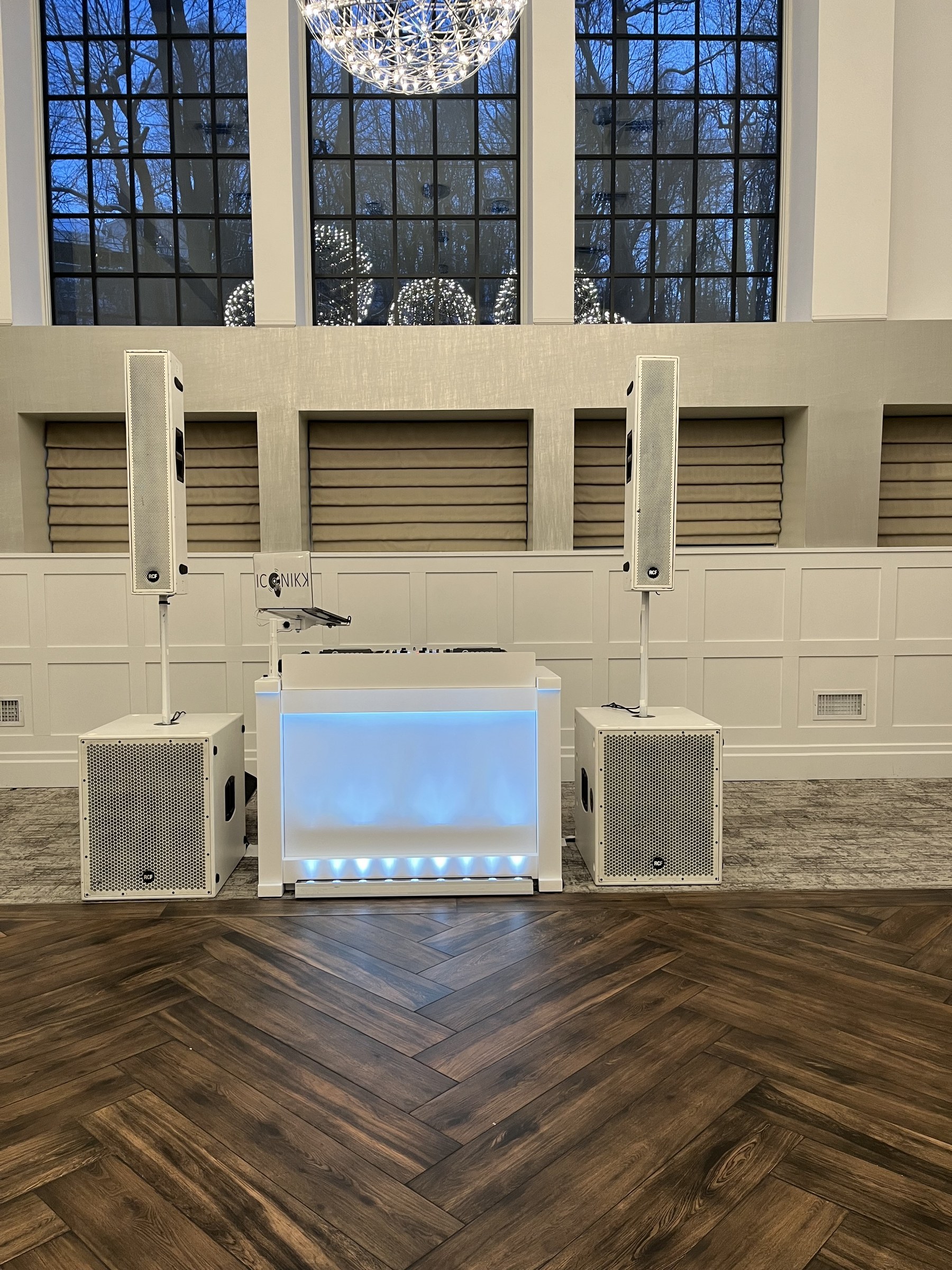 All-white Genesis DJ booth and speaker towers beneath the tall windows at Water's Edge, Centerport